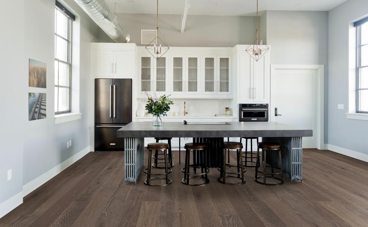 hardwood flooring in kitchen with white cabinets and stone kitchen island with mixed metal decor.